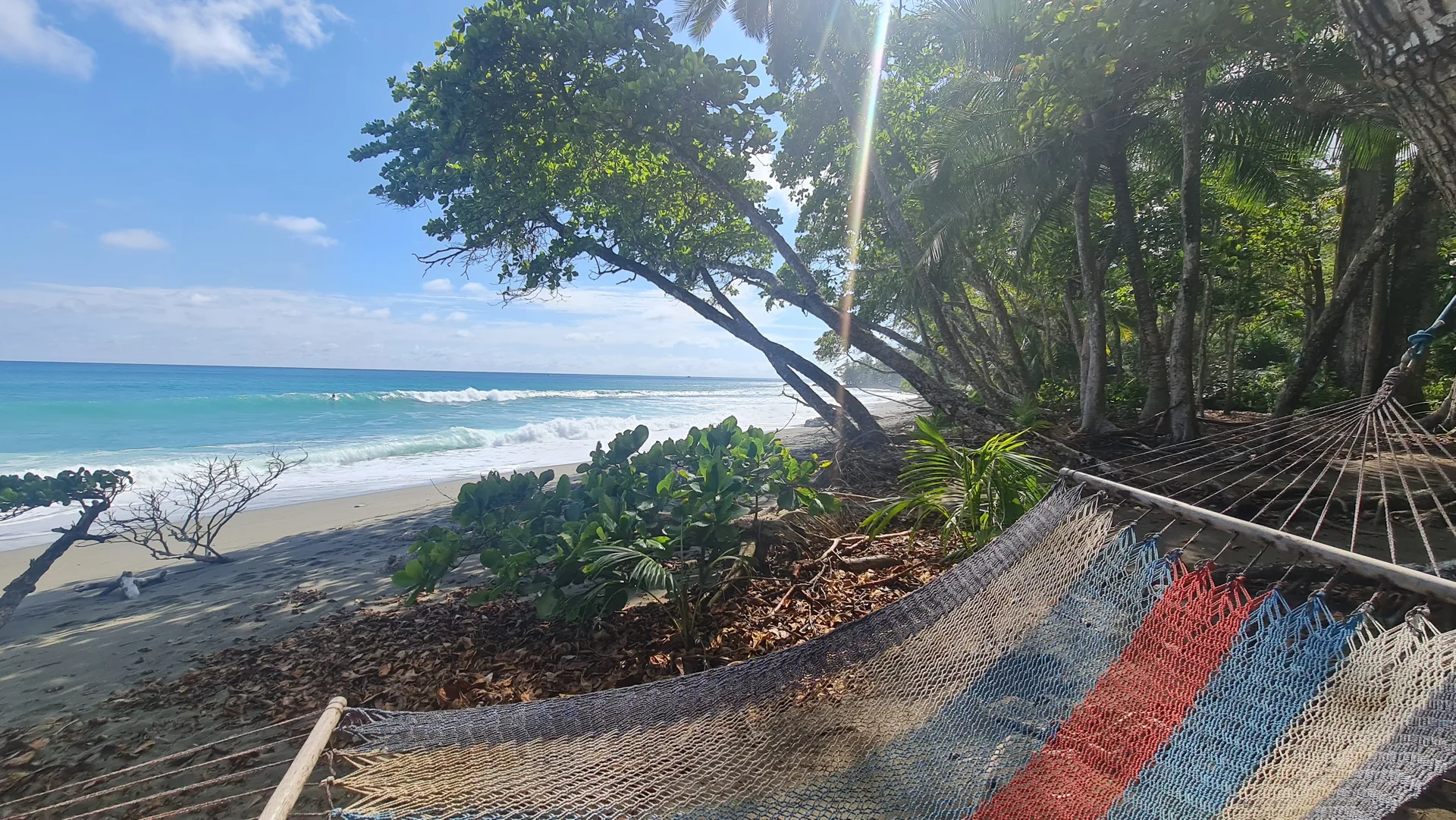 A striped hammock beside the turquoise ocean in Costa Rica